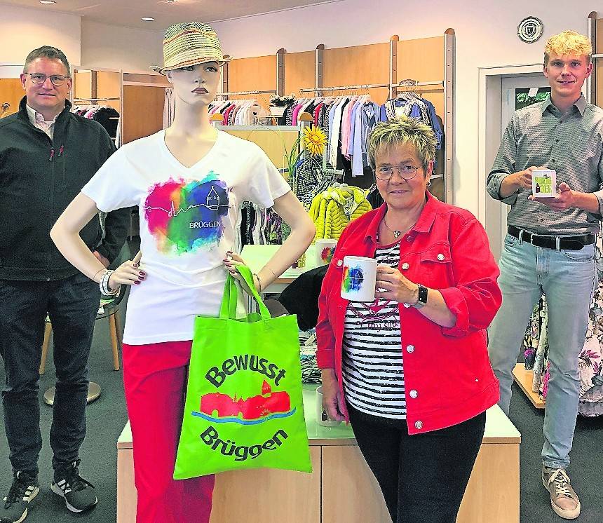  Guido Schmidt, Dominik Seifert (beide Burggemeinde Brüggen) und Petra Metten-Monßen (Mode Metten, v.l.) präsentieren das neue Brüggen Merchandise: Tasse und Shirt. 
