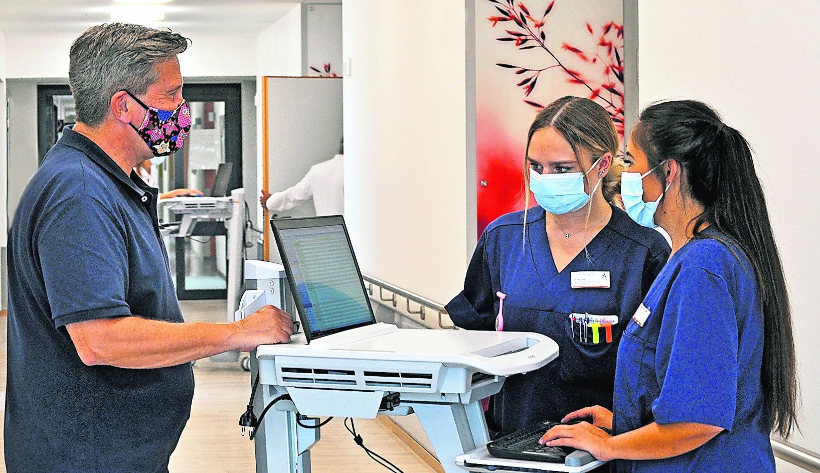  Der stellvertretende Pflegedienstleiter Hans-Peter Wolter (l.) und die freigestellte Praxisanleiterin Sheila Bothe (r.) besprechen mit der Auszubildenden Tajana Schulz die elektronische Dokumentation der Visite. 
