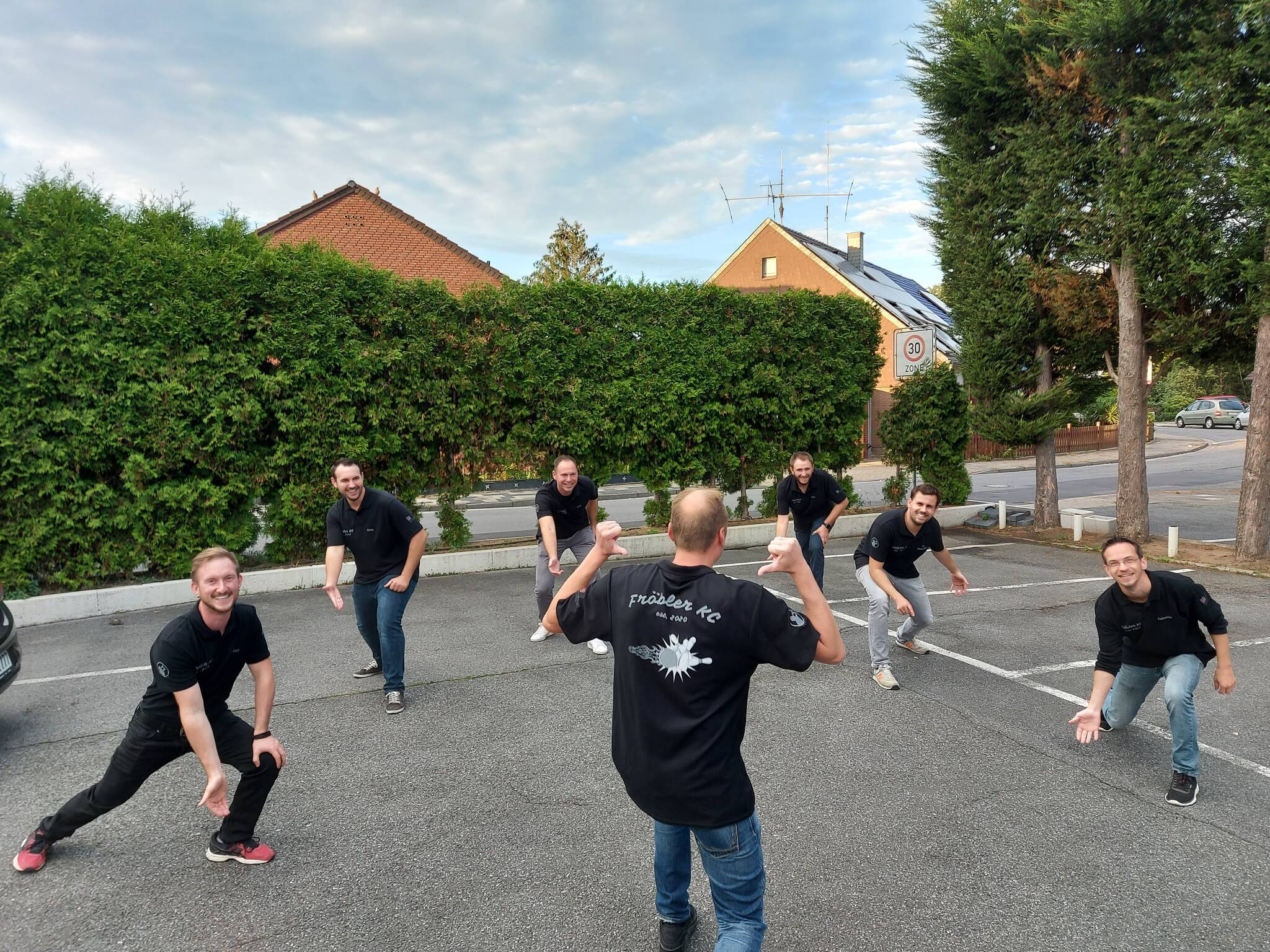 Corona macht erfinderisch: Auf der Kegelbahn der Friedenseiche ist’s zu eng für ein Gruppenfoto, also führen Markus, Pierre, Andre, Richie, Tim und Sebastian ihre besten Kegelmoves einfach auf dem Parkplatz vor. Leo präsentiert derweil das frisch eingetroffene Club-t-shirt, gesponsert von der Bockhold GmbH, dem Bauträger am Fröbelweg. Beim Fotoshooting nicht dabei: Robert.