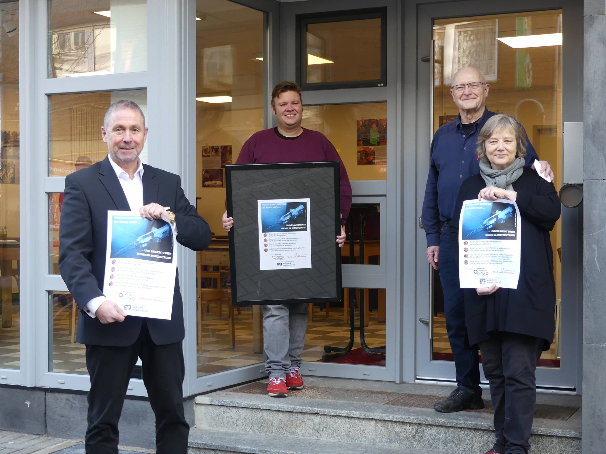  Guido Lohmann (Vorstandsvorsitzender der Volksbank Niederrhein), Sebastian Mörth (Wondervolle Brautmoden) sowie das Ehepaar Wolfram und Anja Reutlinger mit den Plakaten, die auf die Aktion in der Werkstatt Meerbeck aufmerksam machen und in den Geschäften im Ortsteil aufgehangen werden sollen. 