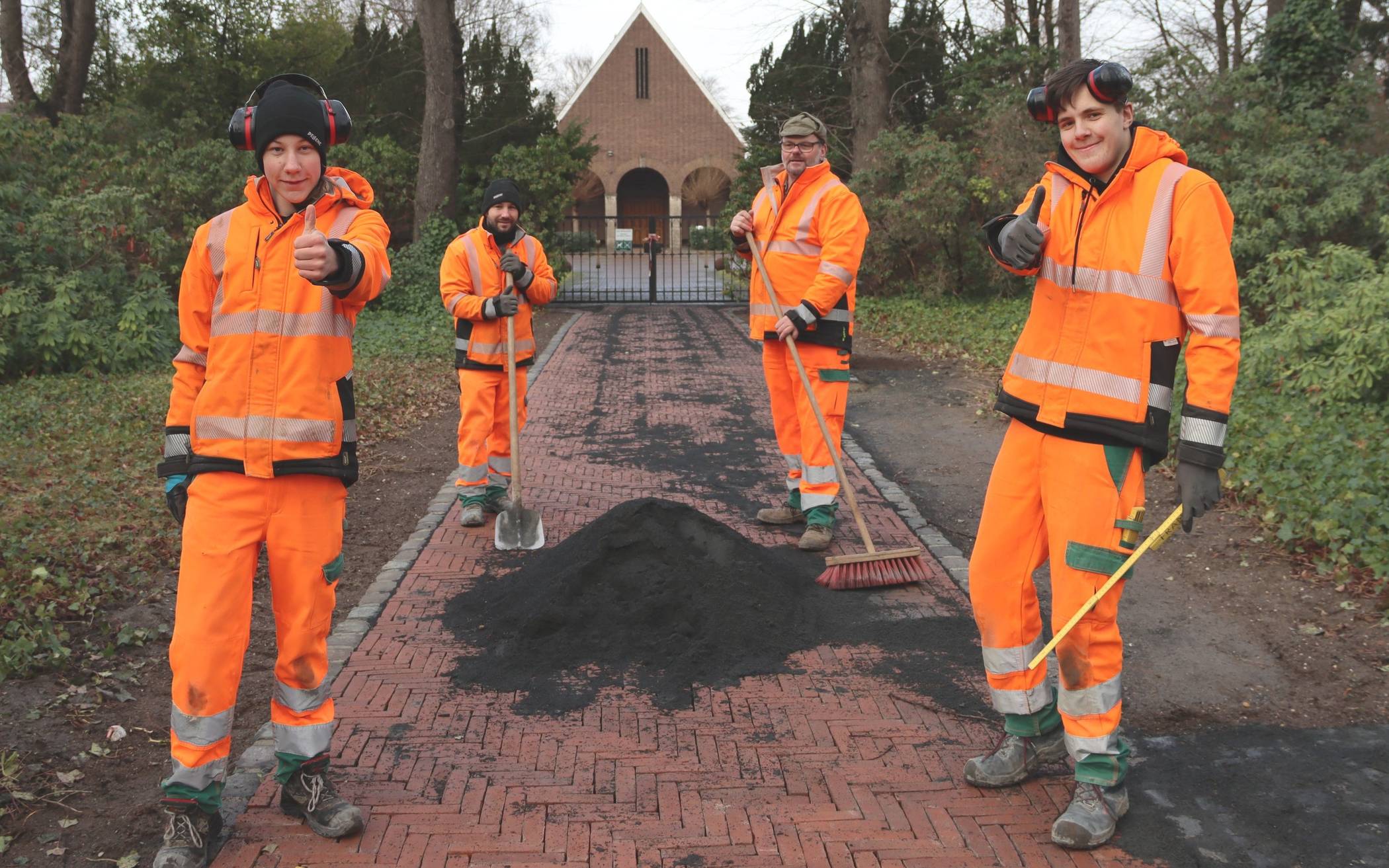  Daumen hoch: Die Azubis Lars Christmann (links) und Michel Querling mit ihren Ausbildern Bernd van Hees und Gerd Schumacher (hinten) sind stolz auf den verschönerten Eingangsbereich des Büdericher Friedhofes. 